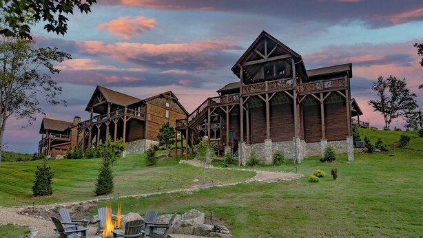 A large wooden lodge with multiple levels and a stone foundation, surrounded by a well-maintained lawn and a fire pit area. - Campfire Trail at Eagles Nest - pet Friendly (Banner Elk)