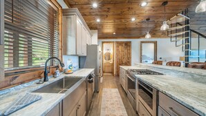 A modern kitchen with wooden beams, stainless steel appliances, and a marble countertop. - Campfire Trail at Eagles Nest - pet Friendly (Banner Elk)