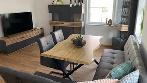 Un salon moderne comprenant un téléviseur, une table à manger, un canapé et des placards intégrés.