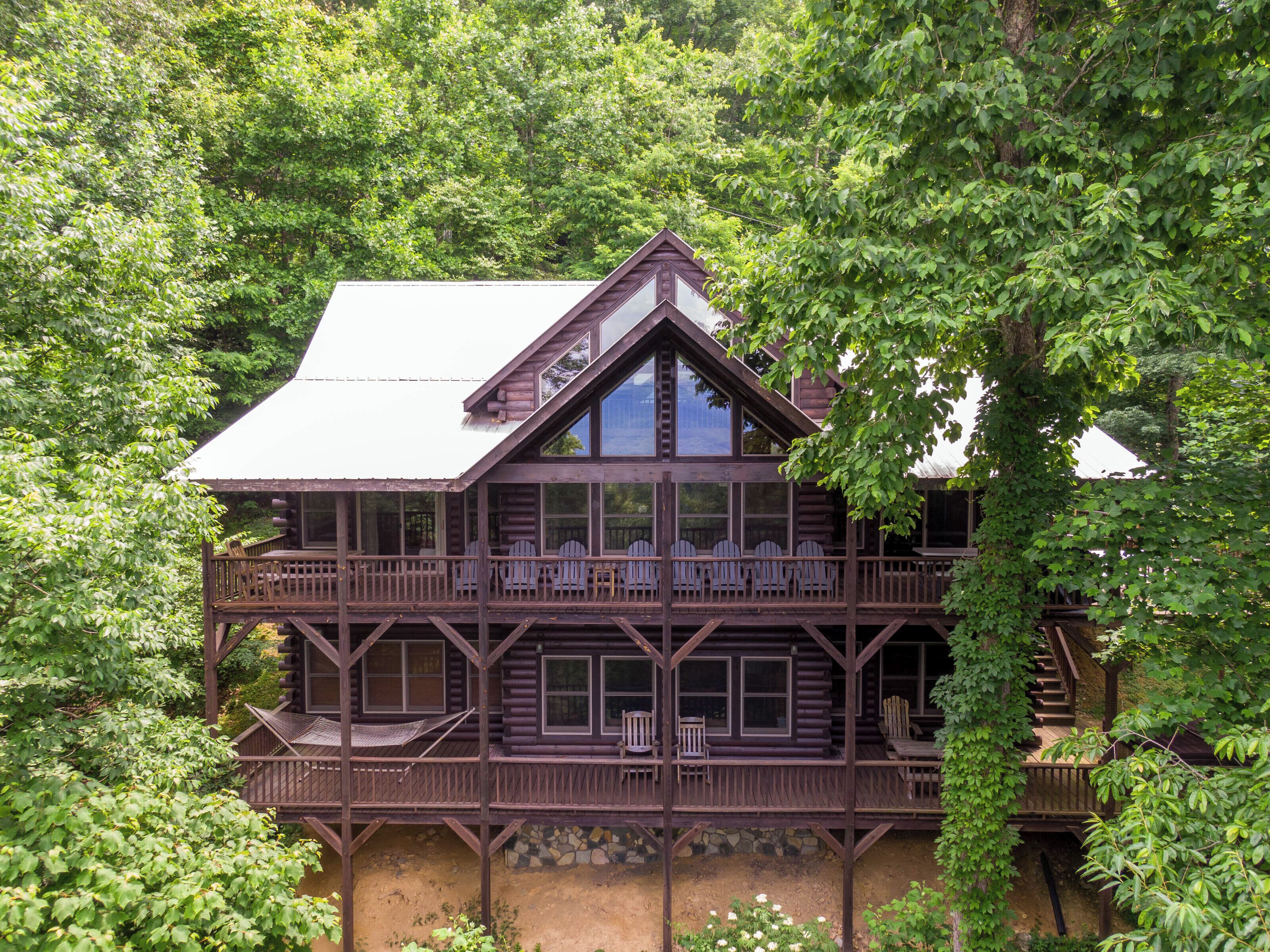 Une cabane en rondins à deux étages, dotée d’un balcon et de nombreuses fenêtres.