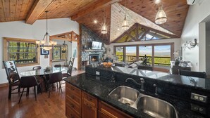 Una cocina amplia con una isla grande, vigas de madera en el techo y vistas al exterior.