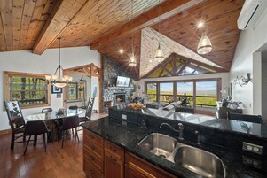 Una cocina amplia con una isla grande, vigas de madera en el techo y vistas al exterior.