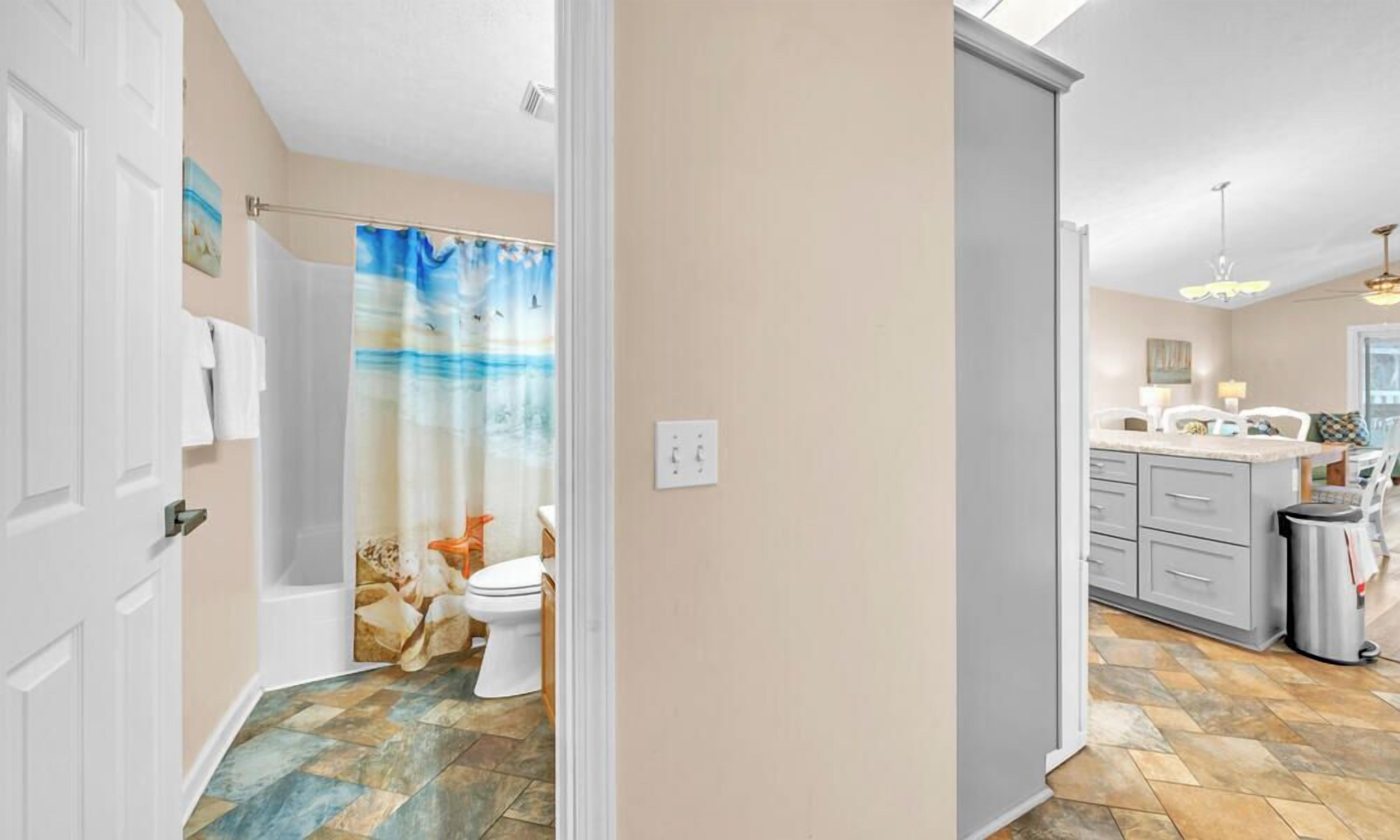 A bathroom with a shower curtain, toilet, and a tiled floor.