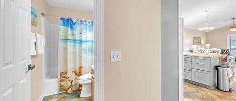 A bathroom with a shower curtain, toilet, and a tiled floor.