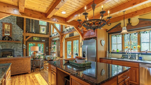 A spacious kitchen with wooden beams, a stone fireplace, and a large island with granite countertops. - D-coys Nest (Banner Elk)