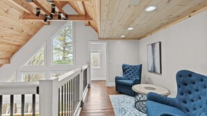 A spacious loft with a wooden ceiling, large windows, and blue upholstered chairs. - Elevation Escape (Banner Elk)