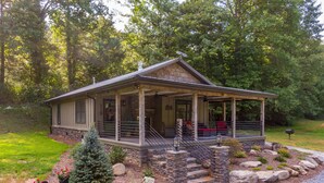 A rustic cabin with a porch, stone steps, and a small Christmas tree. - Up the Creek (Linville)
