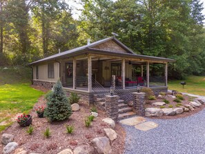 A rustic cabin with a porch, stone steps, and a small Christmas tree. - Up the Creek (Linville)