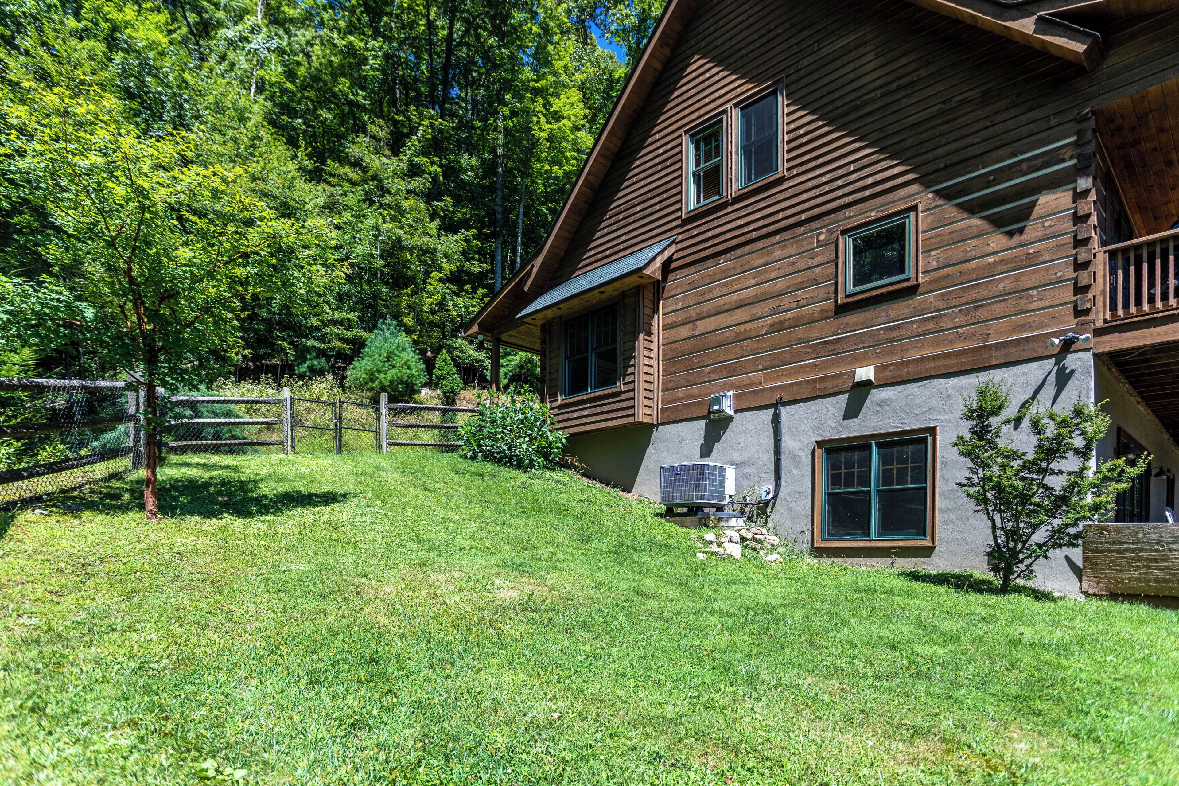 A wooden cabin with a sloped roof, a fenced yard, and a solar panel.