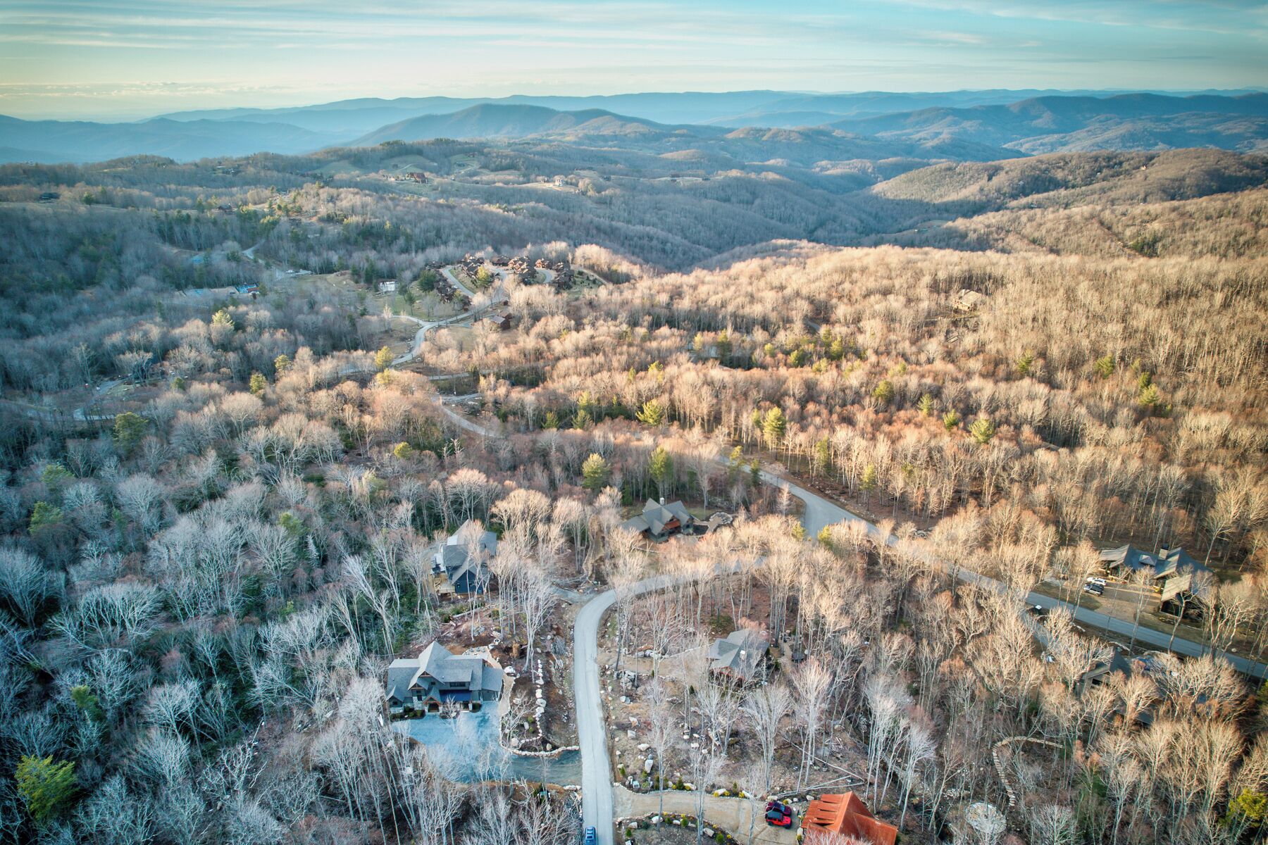 A mountainous landscape with a winding road, a house, and a small building.