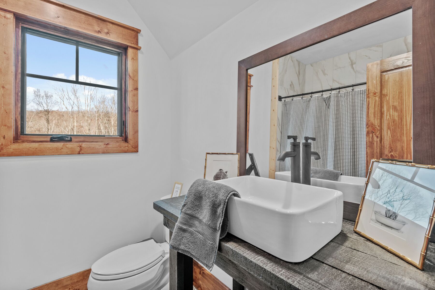 Une salle de bain avec une fenêtre, un lavabo, des toilettes et un miroir.