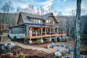 Eine große, mehrstöckige Holzhütte mit überdachter Veranda und Sitzbereich im Freien.