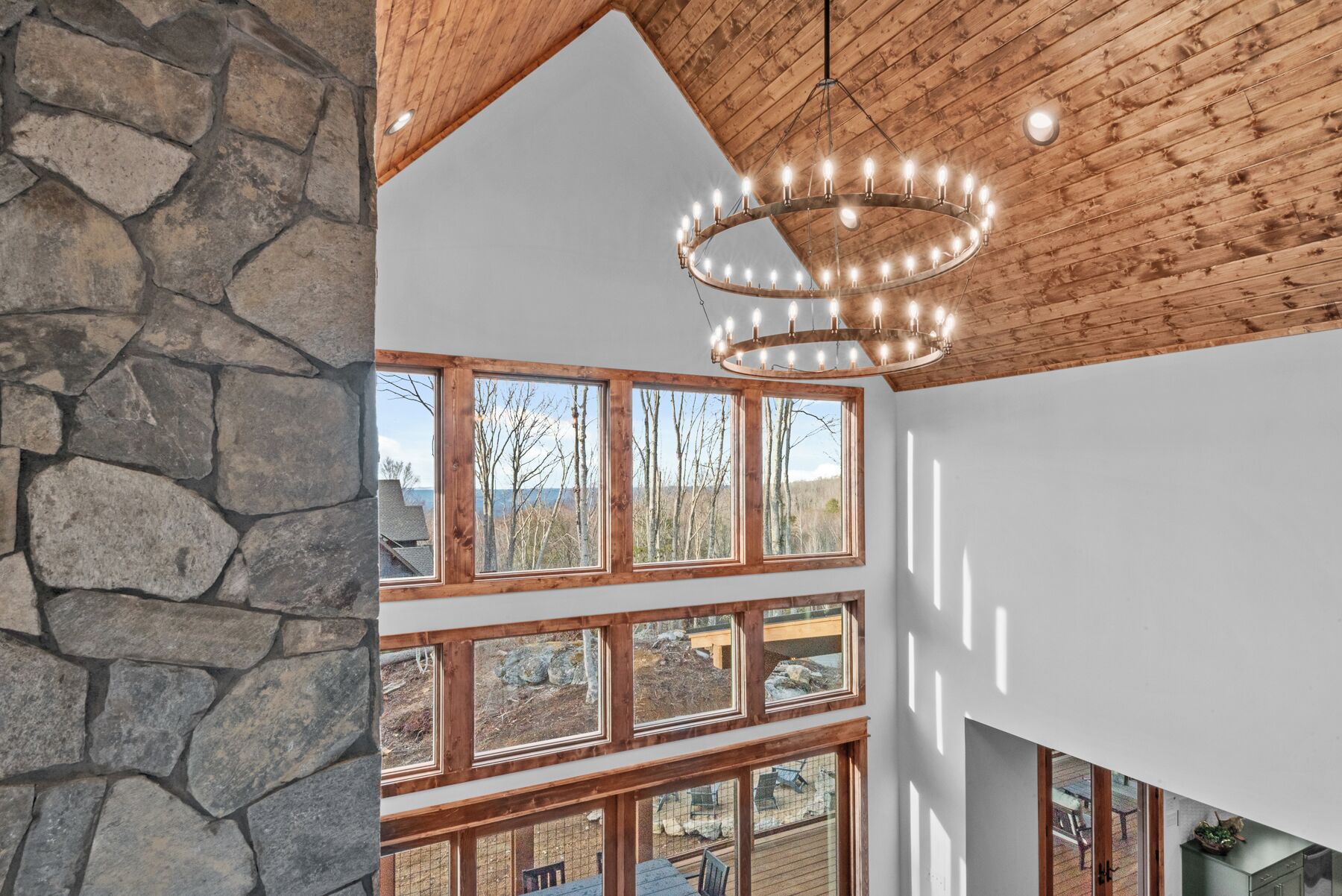 A multi-level interior with stone walls, wooden beams, and a chandelier.