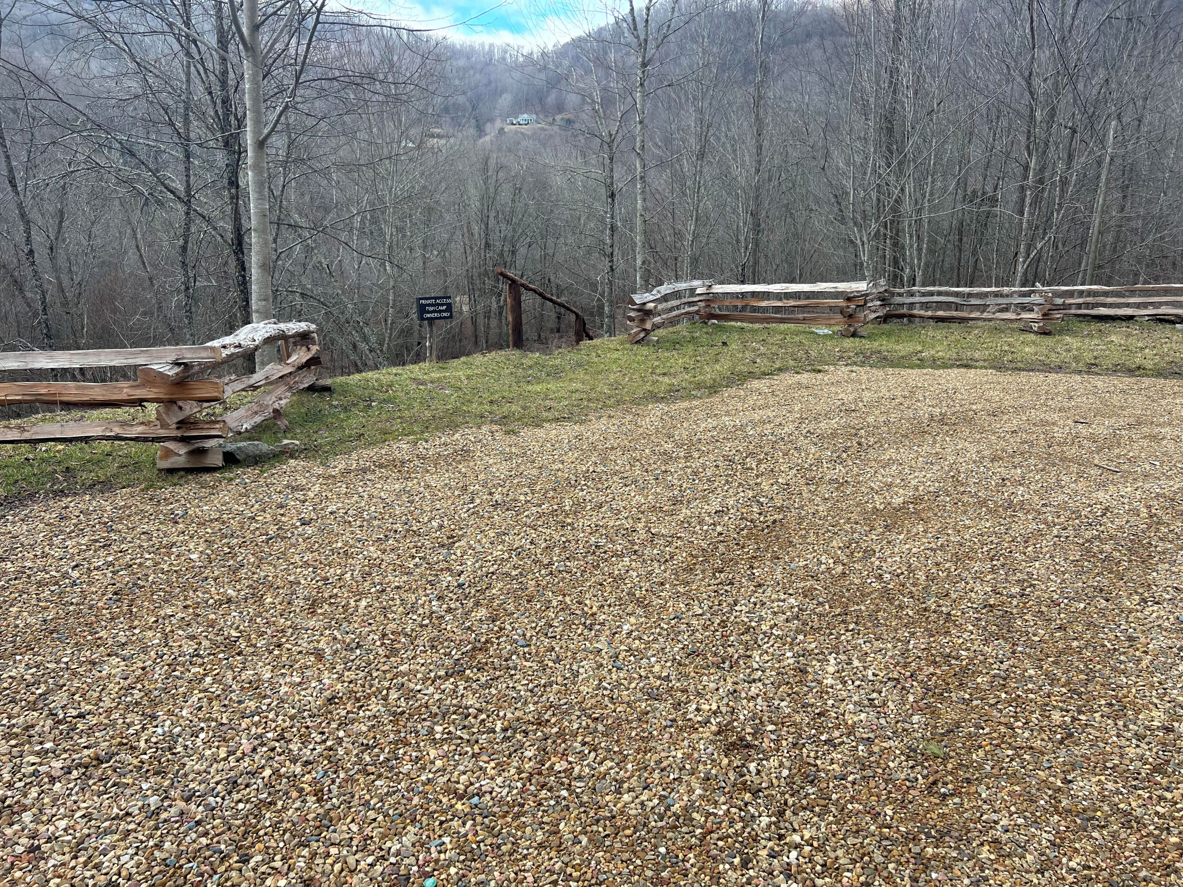 A gravel path leading to a wooden fence with a sign indicating private access.