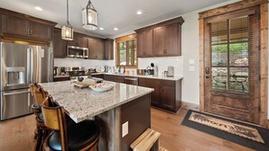A modern kitchen with granite countertops, stainless steel appliances, and wooden cabinets. - Song on the Mountain at Eagles Nest (Banner Elk)