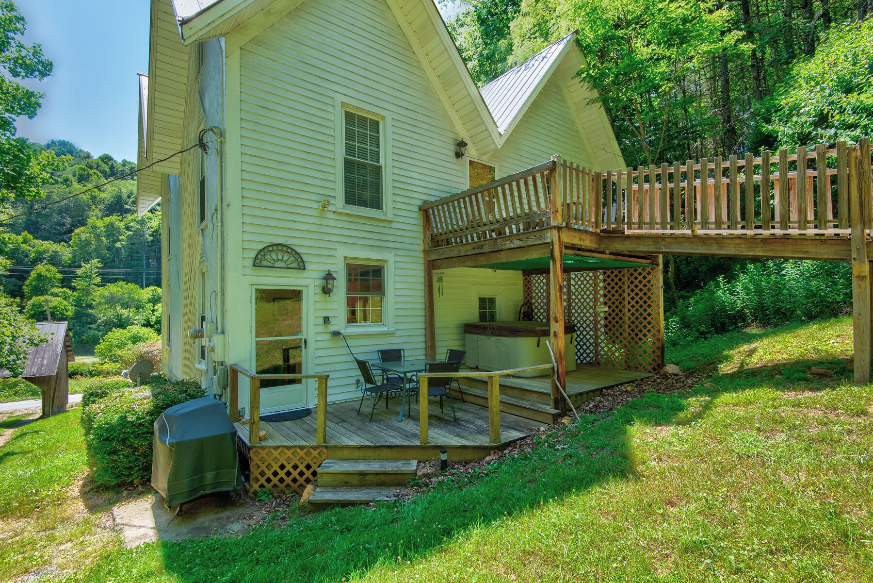 A two-story house with a deck and a covered outdoor seating area.