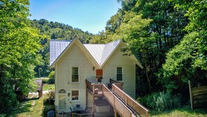 Ein zweigeschossiges Haus mit Veranda, Treppe und einer kleinen Terrassenfläche.
