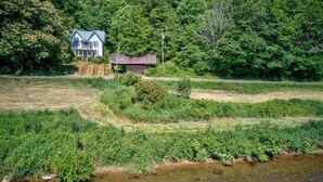 Ein Haus mit blauem Dach und weißen Wänden, umgeben von üppiger Vegetation und einer kleinen Holzhütte.