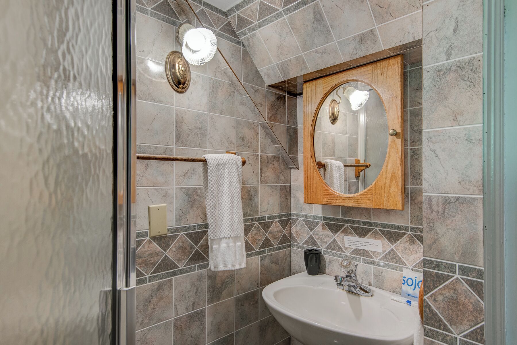 A bathroom with a sink, mirror, towel rack, and a shower area.