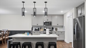 A modern kitchen with white cabinets, a stainless steel refrigerator, and a central island with bar stools.