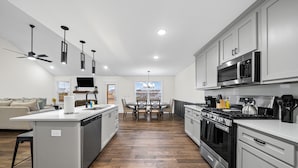 A modern kitchen with white cabinets, stainless steel appliances, and a central island.