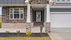 A two-story house with a stone facade, a front porch, and a garage.