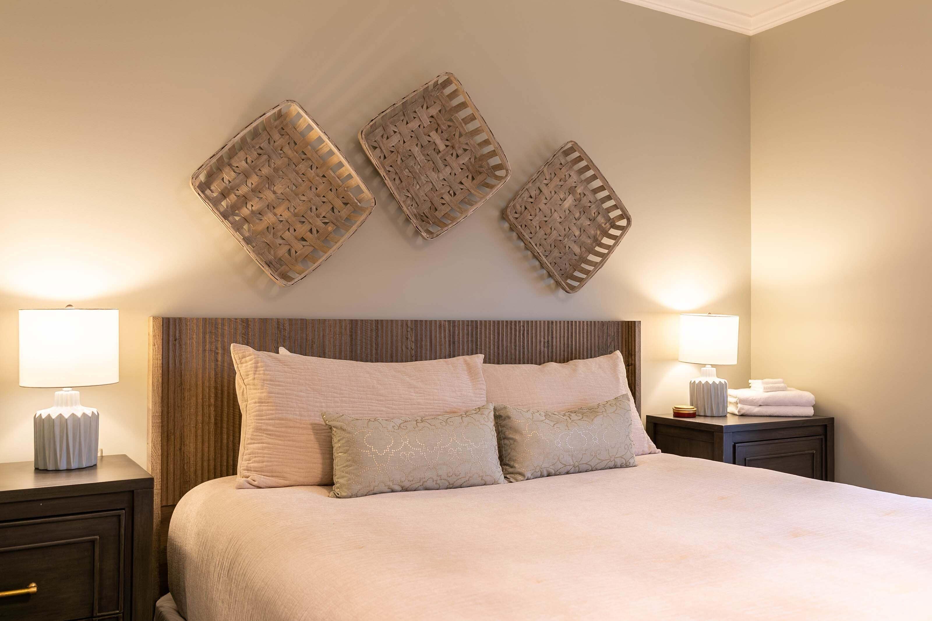 A neatly made bed with pillows, a bedside lamp, and a nightstand with a lamp.