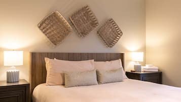 A neatly made bed with pillows, a bedside lamp, and a nightstand with a lamp.