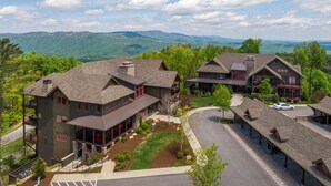 A large, multi-story hotel with a central courtyard, surrounded by lush greenery and mountains in the background.