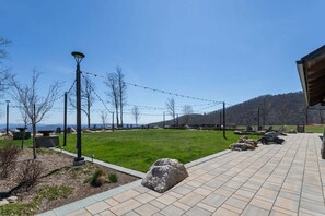 A paved outdoor area with seating, string lights, and a view of distant mountains. - Cozy Mountain Retreat at Blue Ridge Mountain Club (Boone)