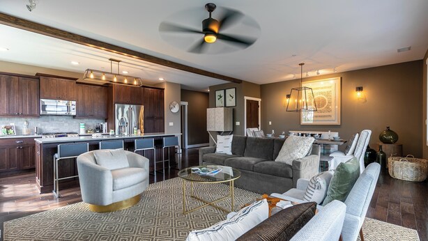 A modern living room with a sofa, coffee table, and a dining area with a kitchen in the background.