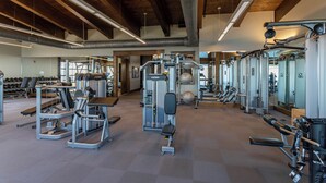 A spacious gym with various exercise equipment, wooden beams on the ceiling, and a clean, modern design.