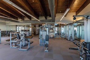 A spacious gym with various exercise equipment, wooden beams on the ceiling, and a clean, modern design.