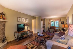 A cozy living room with a fireplace, a television, and a dining area with a chandelier.