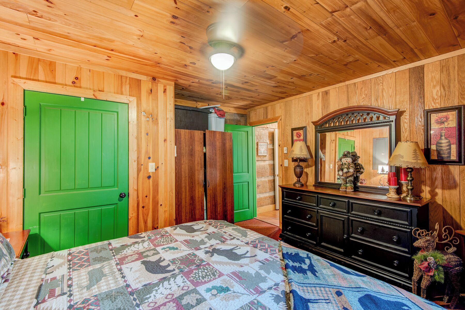 A wooden-paneled room with a bed, dresser, and a mirror.