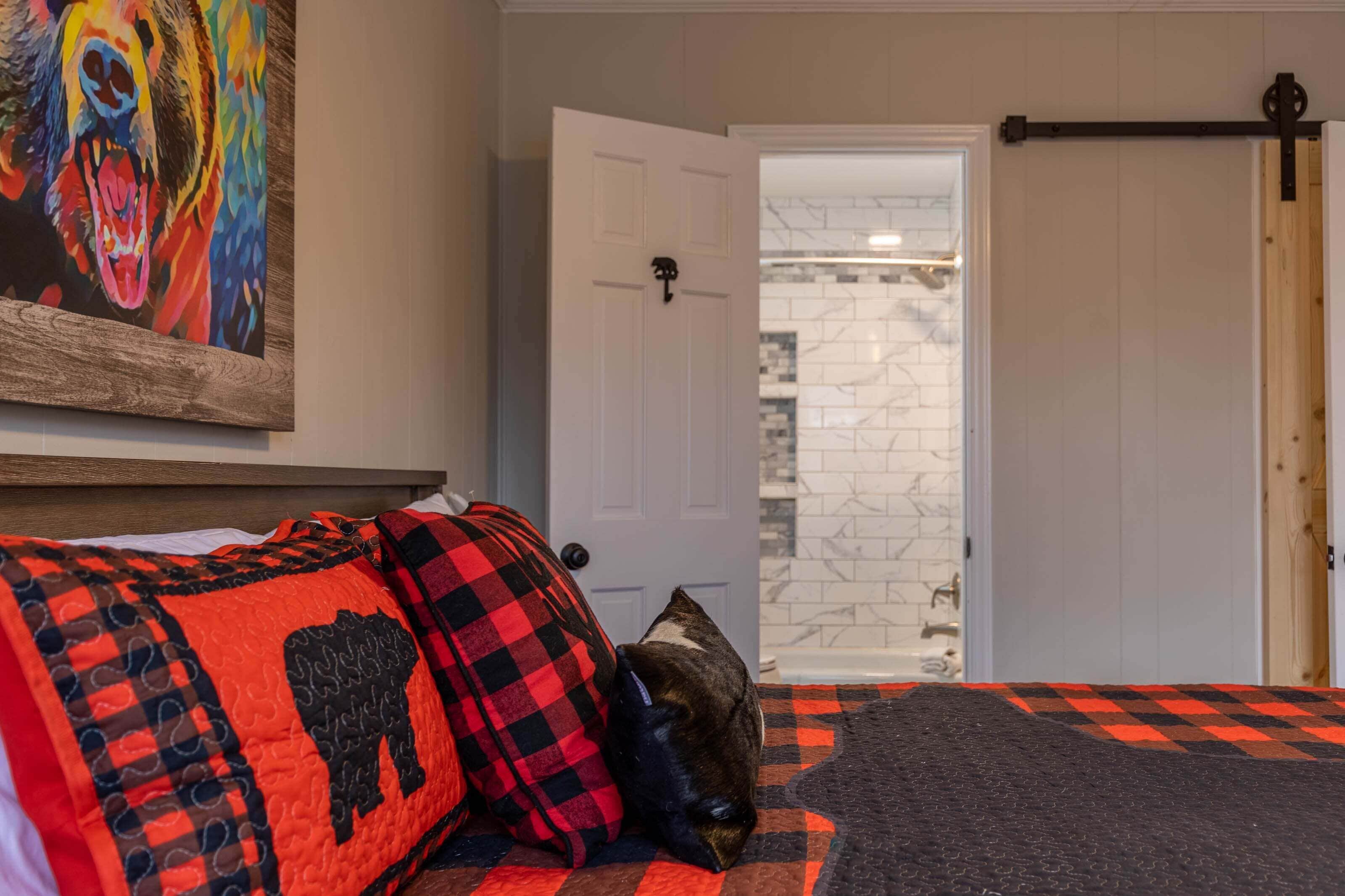 Un dormitorio con cama, un cuadro, una puerta y vistas al baño.