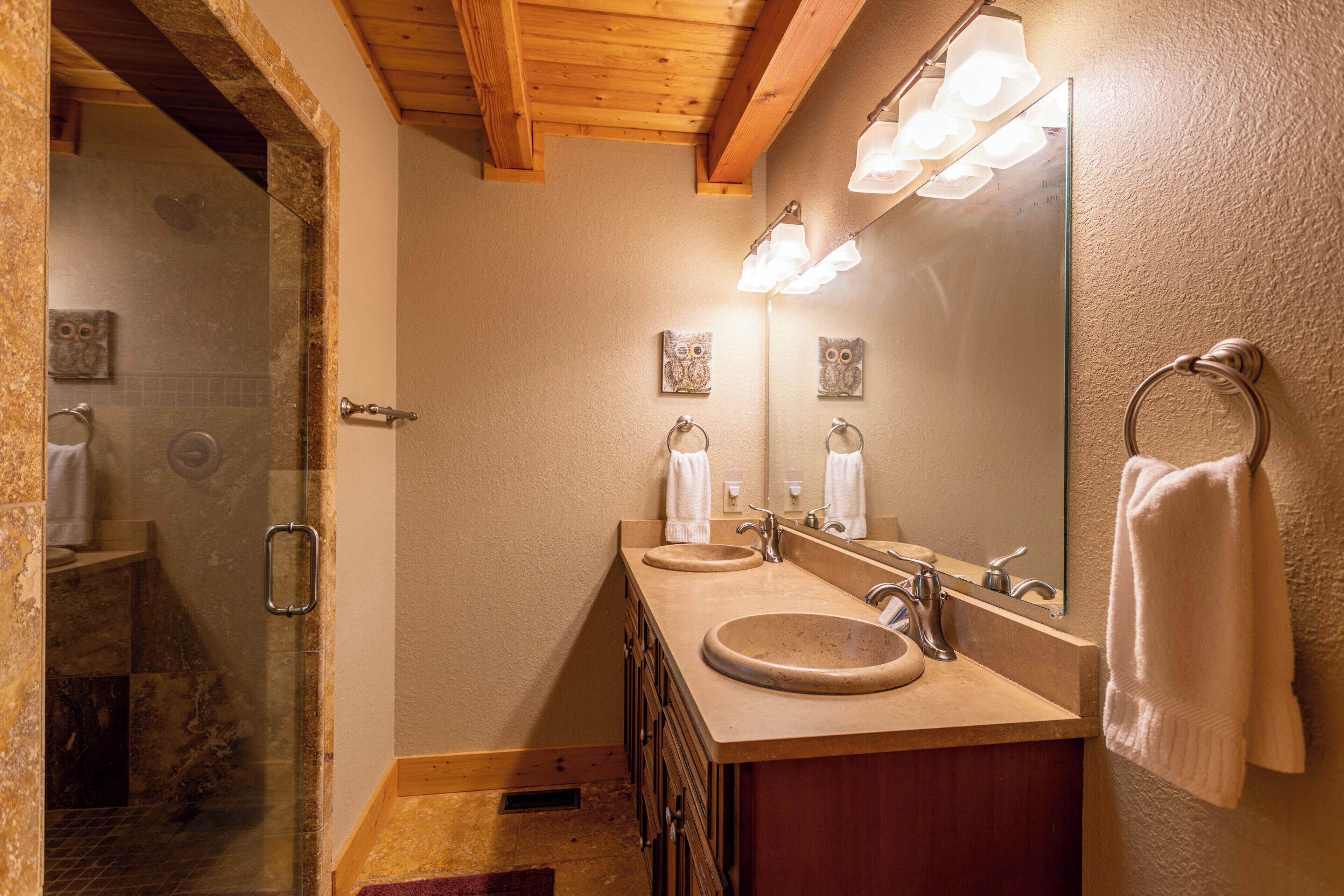 Une salle de bain avec deux lavabos, un grand miroir et un espace douche.