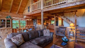 A spacious log cabin interior with a large wooden staircase, a cozy living area with a sectional sofa, and a kitchen with wooden cabinets. - Apple of my Eye (Banner Elk)