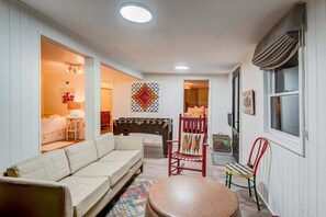 A cozy living room with a sofa, a red chair, a round ottoman, and a small table. - Orchid Cabin (Banner Elk)