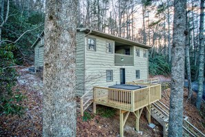 A cabin with a balcony, a deck, and a staircase leading to the entrance. - Orchid Cabin (Banner Elk)