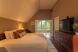 A bedroom with a large bed, a dresser, a television, and a view of the outdoors. - Sky High Chalet Blowing Rock Home With hot Tub, Pool Table, Bunk Room, and Fire pit (Blowing Rock)