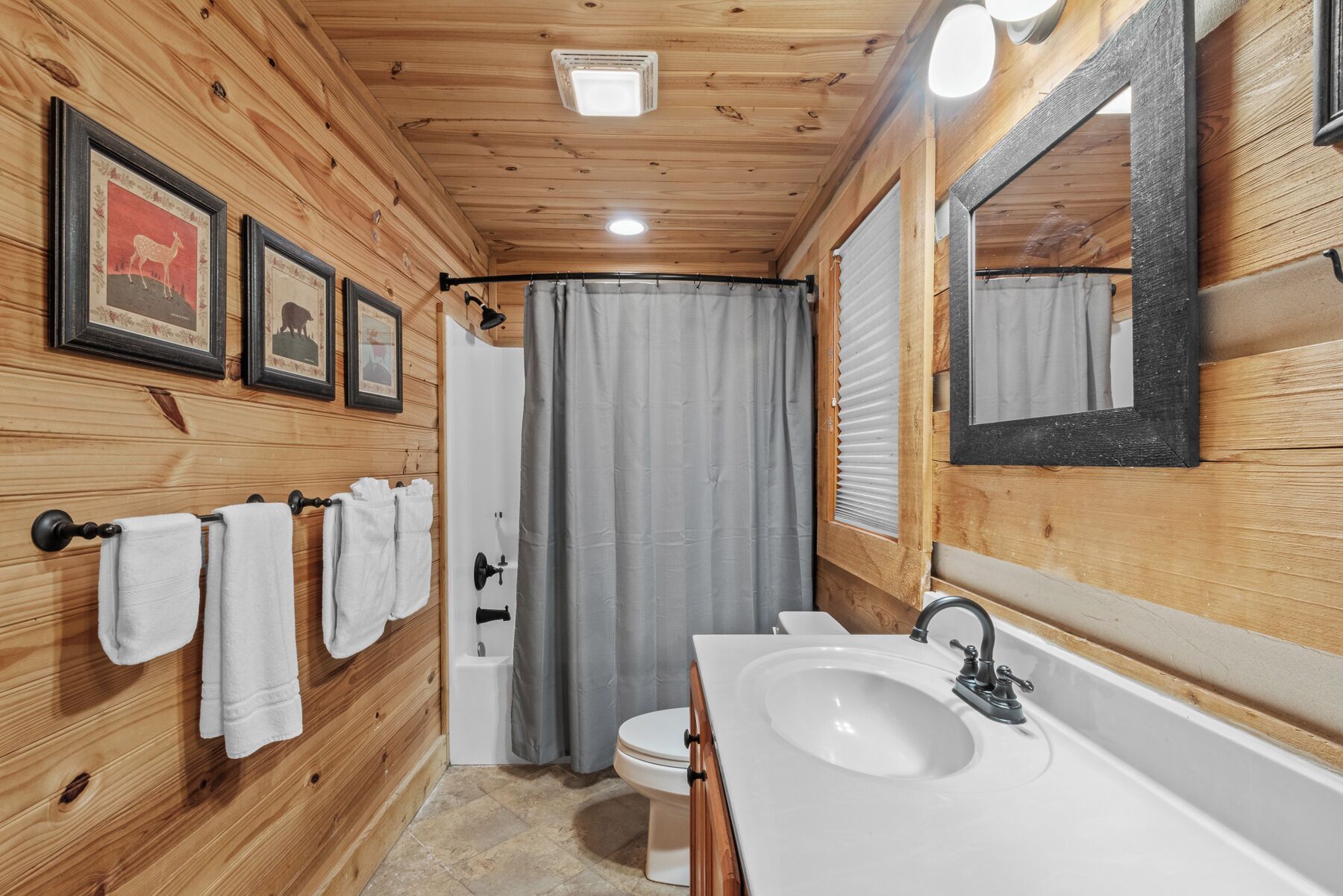 Een houten badkamer met een wastafel, toilet en douchegordijn.