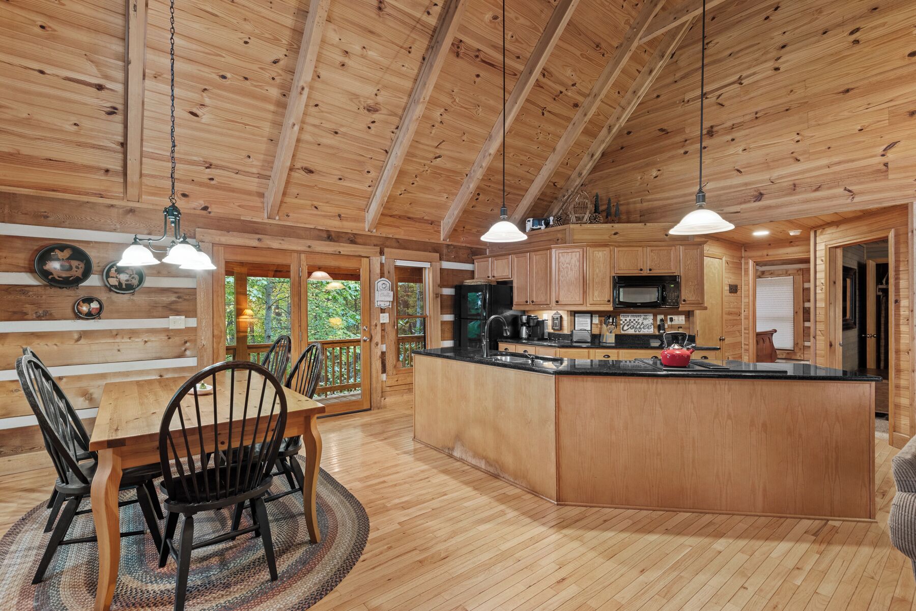 Un intérieur en bois comprenant un coin repas, une cuisine et de grandes fenêtres.