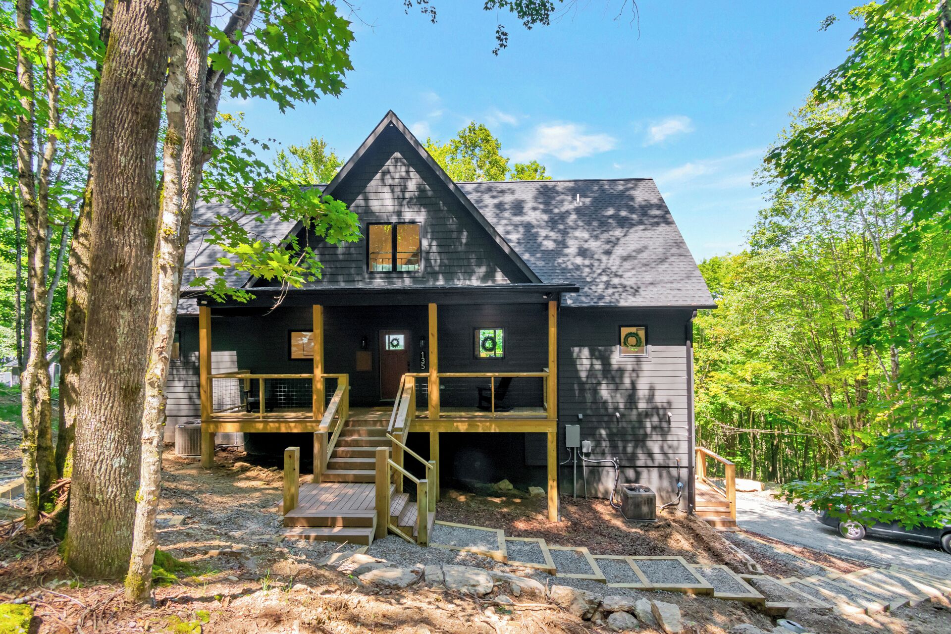 A cabin with a wooden deck, a staircase leading to a porch, and a natural forest setting.