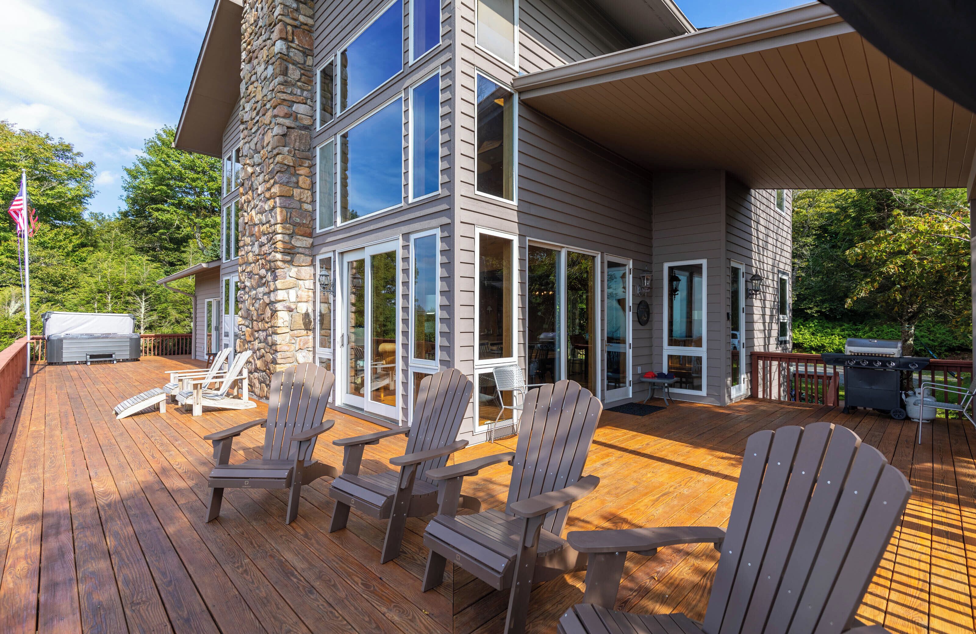 A multi-story house with a wooden deck, stone pillar, and large windows.