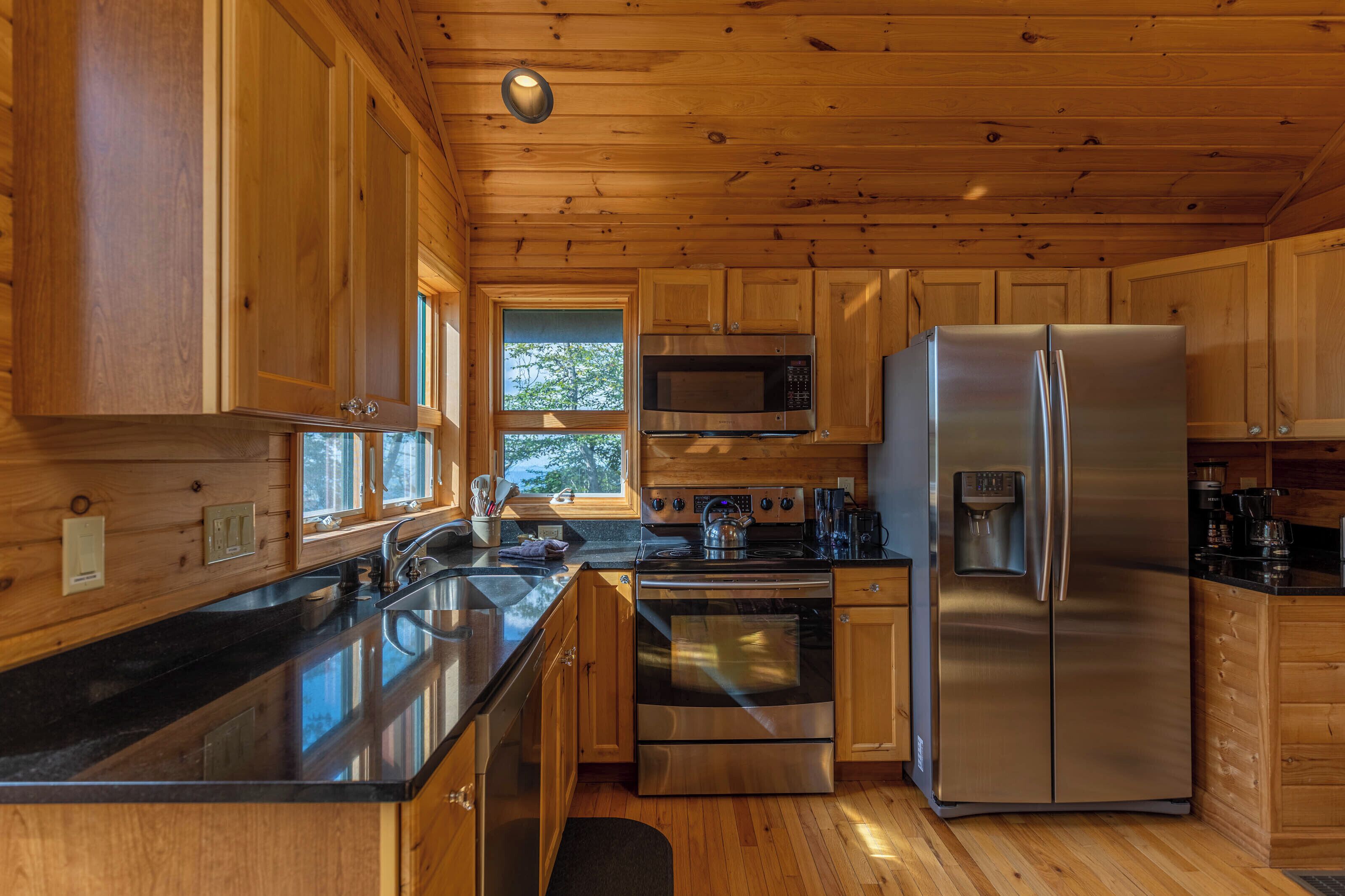 A modern kitchen with wooden cabinets, stainless steel appliances, and a black countertop.