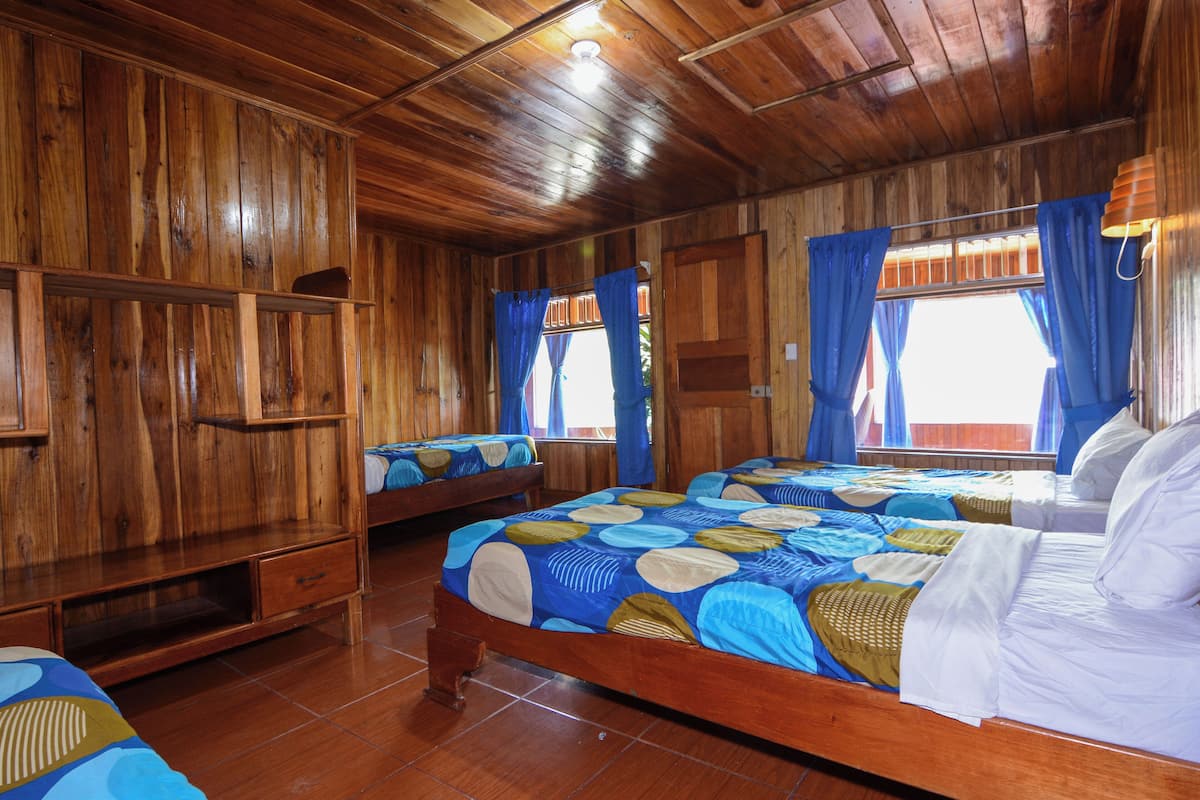 Una habitación de madera con dos camas, un armario de madera y una ventana con cortinas.
