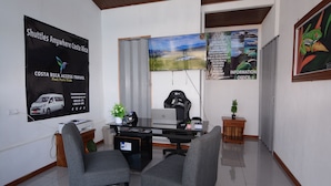 Una oficina moderna con un escritorio, dos sillas, una laptop, un monitor de computadora, una planta y un cartel en la pared.