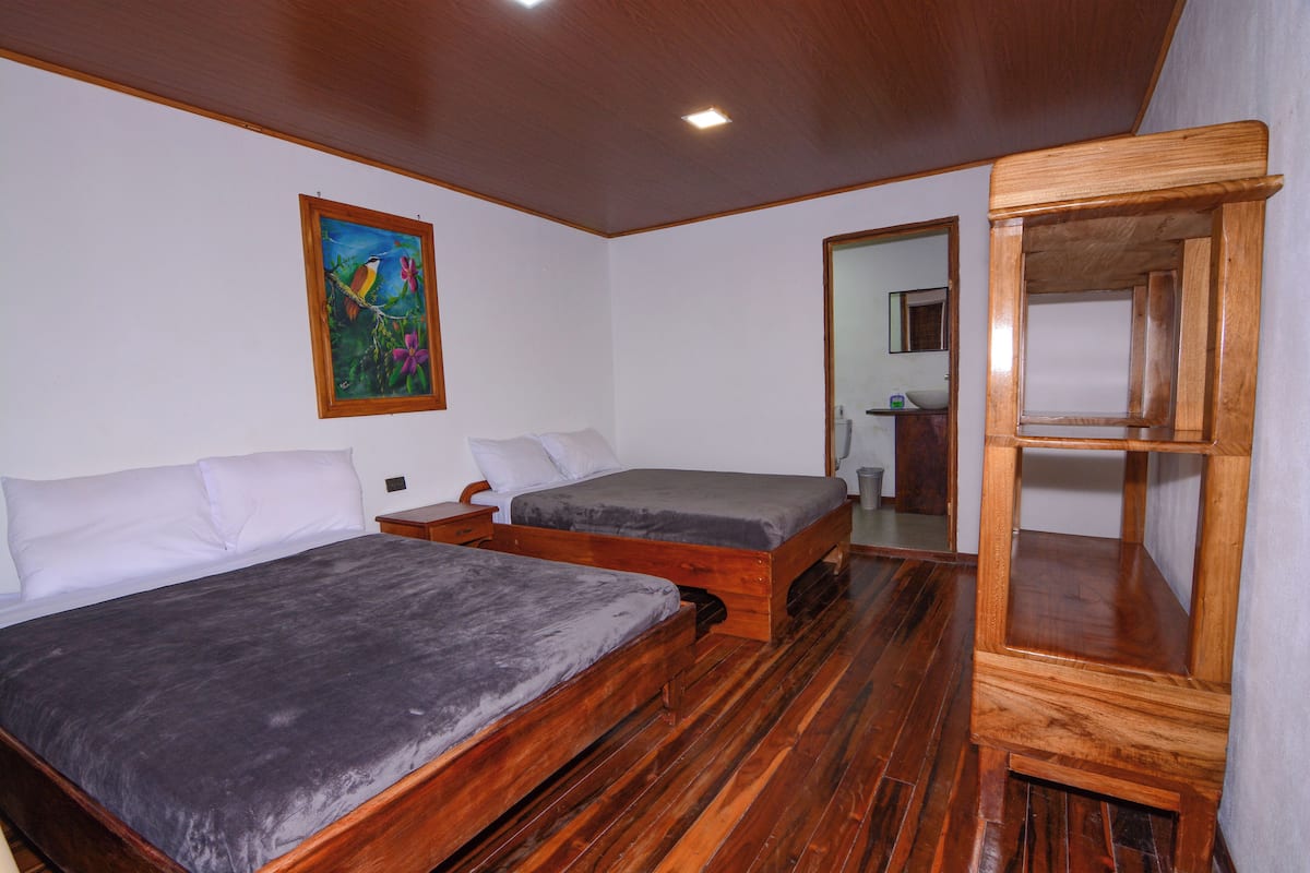 Una habitación con dos camas de madera, un armario de madera y un cuadro en la pared.