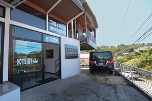 A hotel with a sign for tours and shuttle services, a glass entrance, and a vehicle parked outside.